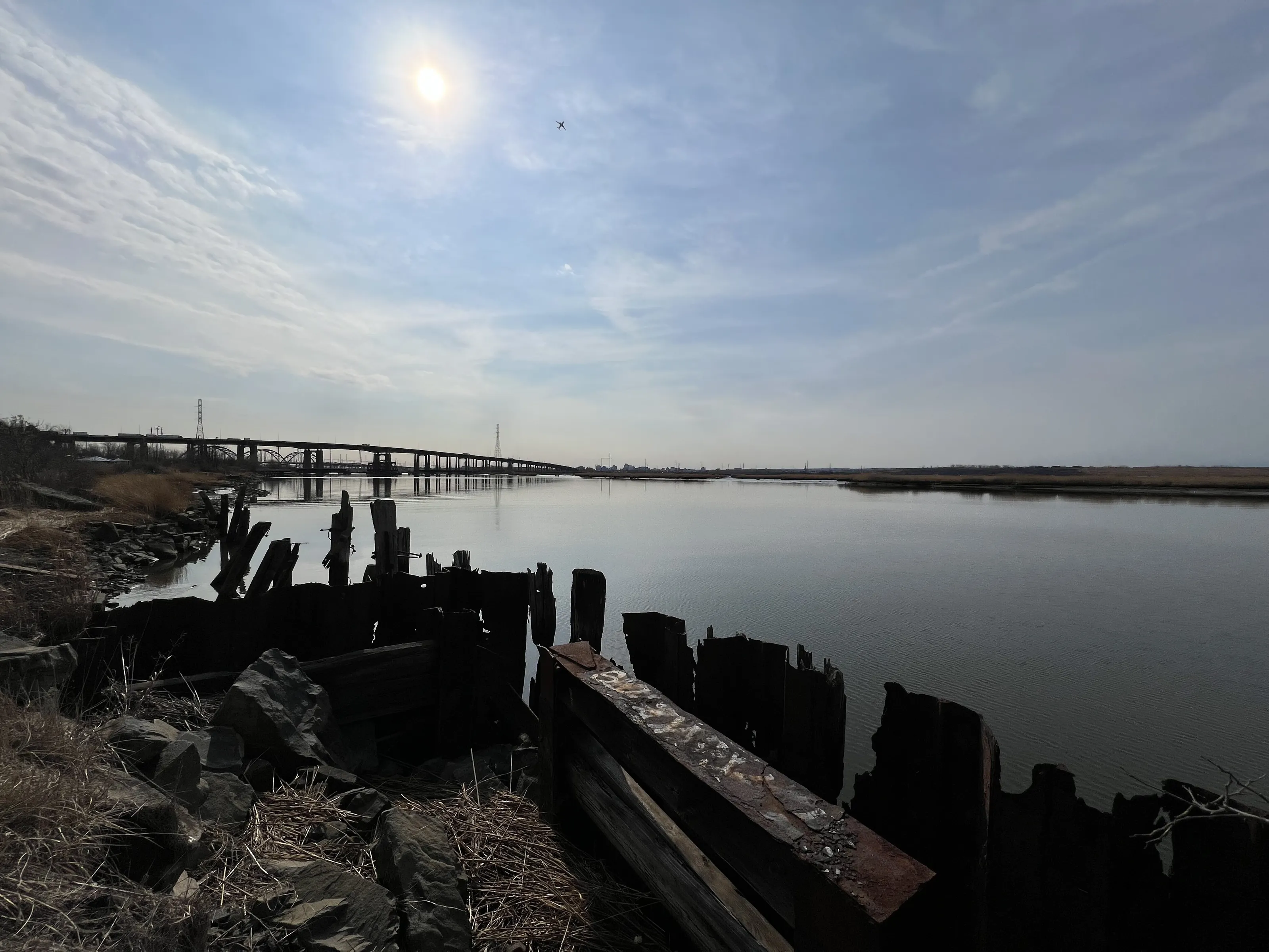 Overlooking a broken dock to see a bridge heading over the river