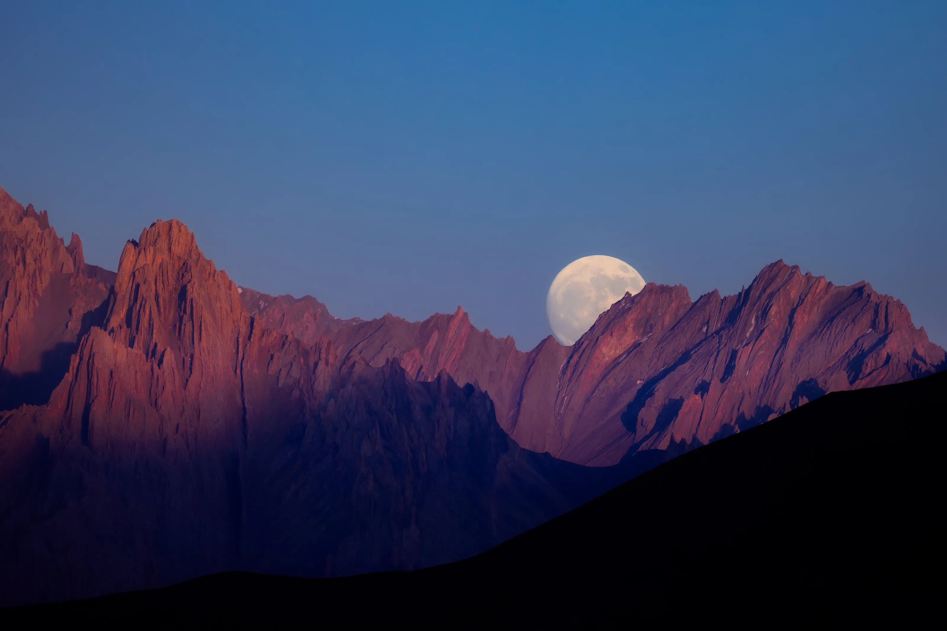 The moon slowly rising above the mountains