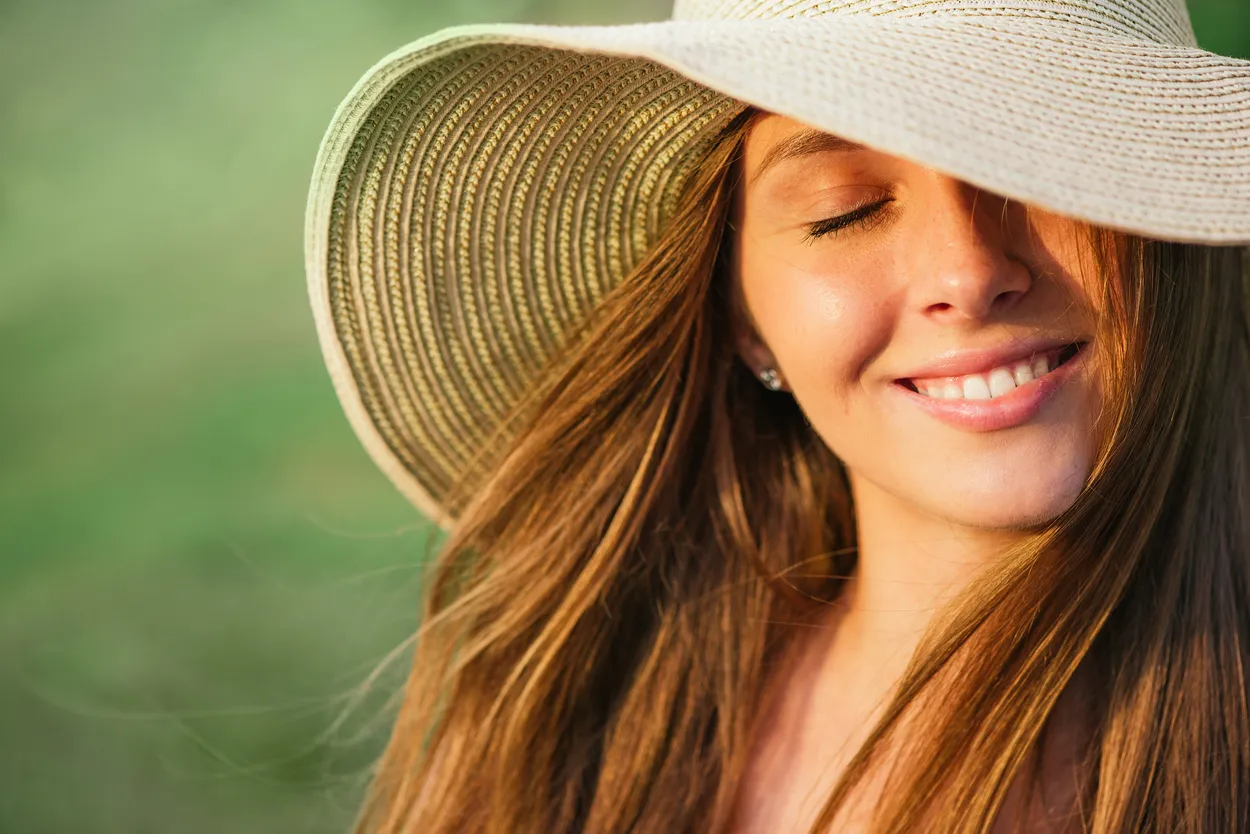Summer head shot of happy young woman on green background in hat . Model with closed eyes