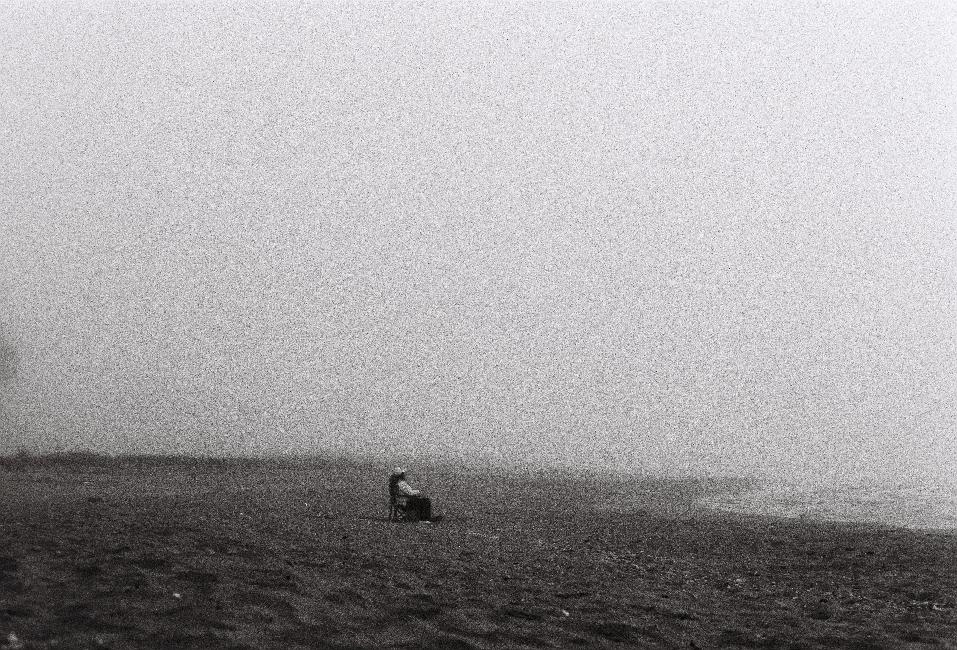A woman awaits the sunrise on a foggy morning at Krapets Beach, Bulgaria