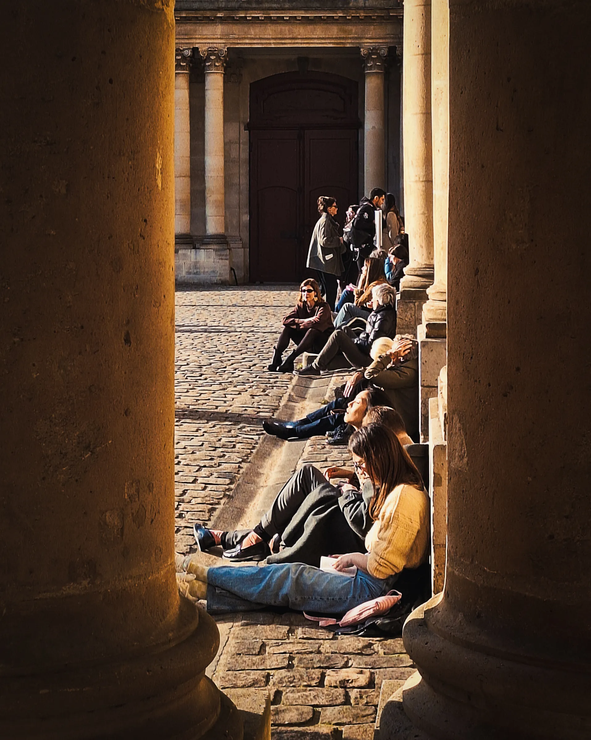 People are sitting down along the side of Museum de Archives in Paris