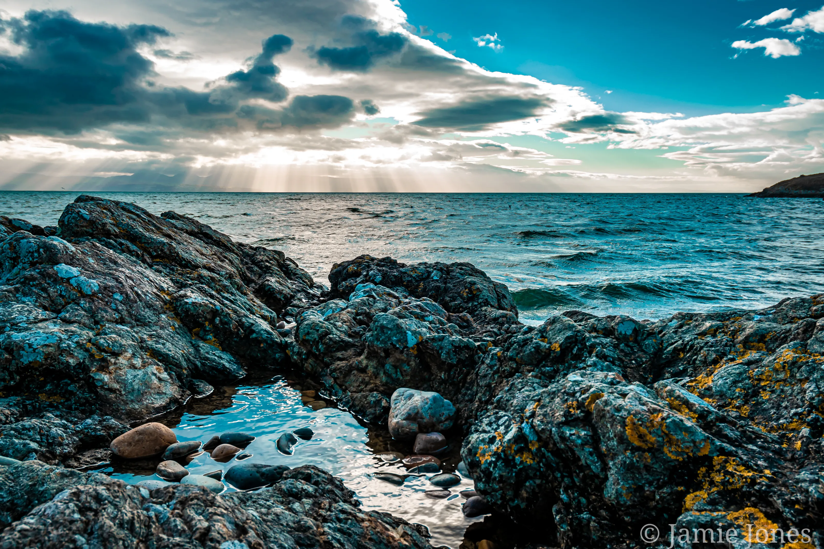 Blue sea and sky reflecting of the rocks.