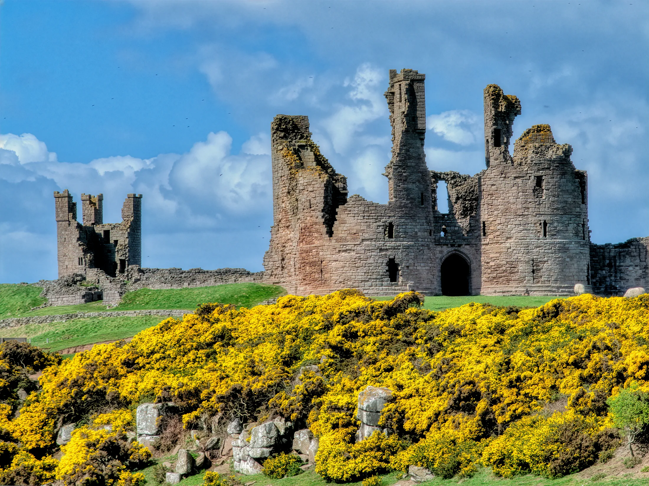 Dunstanburgh Castle is a 14th-century fortification on the coast of Northumberland