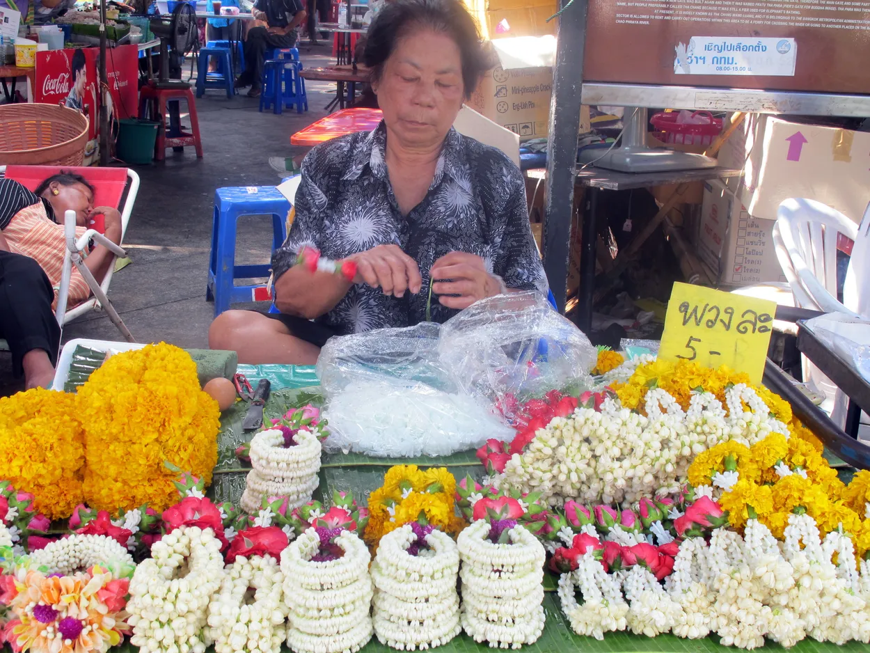 Woman making and selling flower garland offerings, Bangkok, Thailand