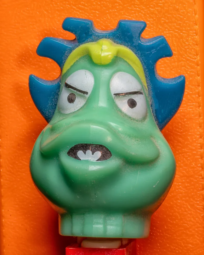Pez Dispenser Head on Orange Plastic Background
