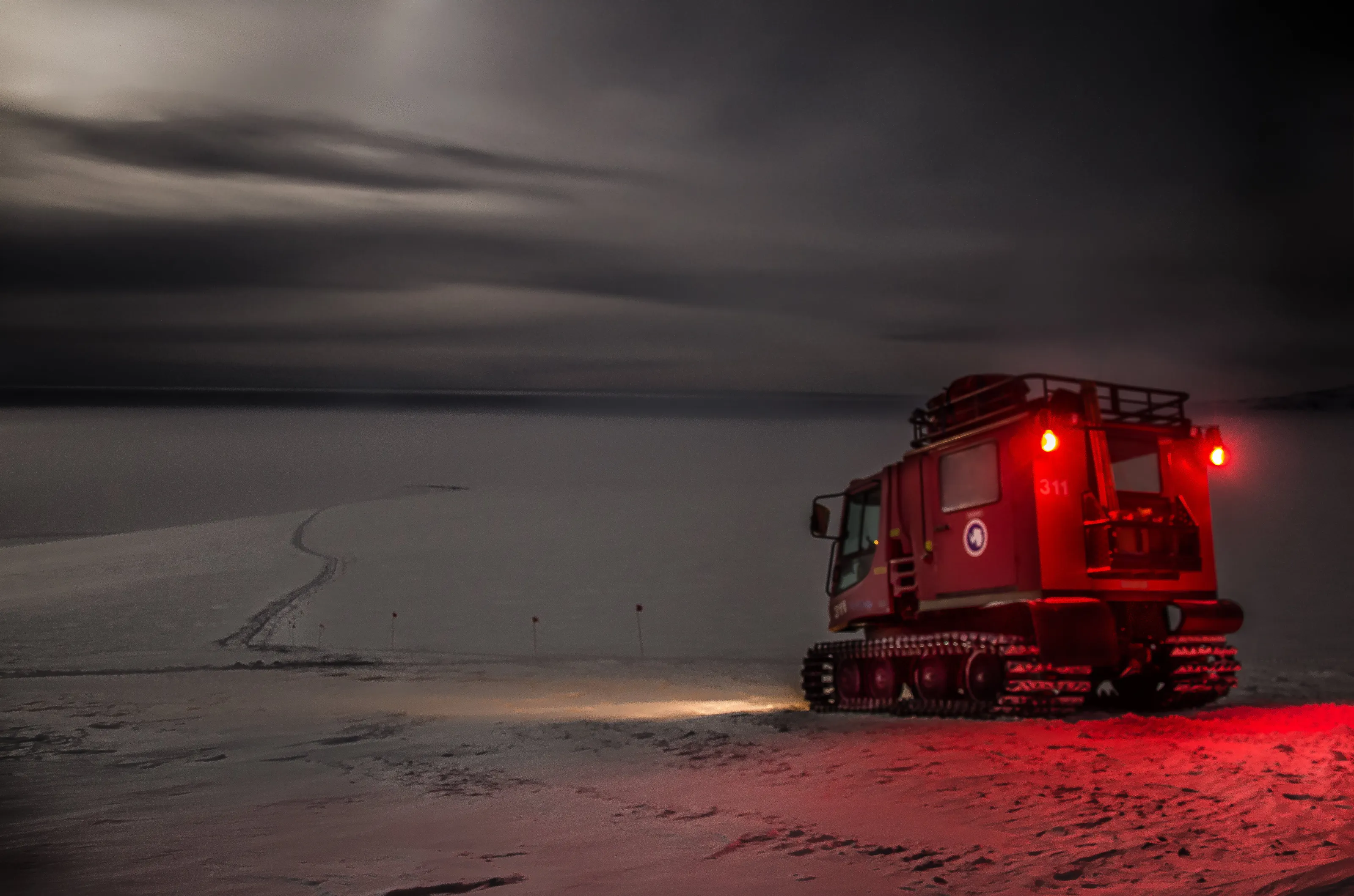 A pistenbully at noon on a dark Antarctic winter day