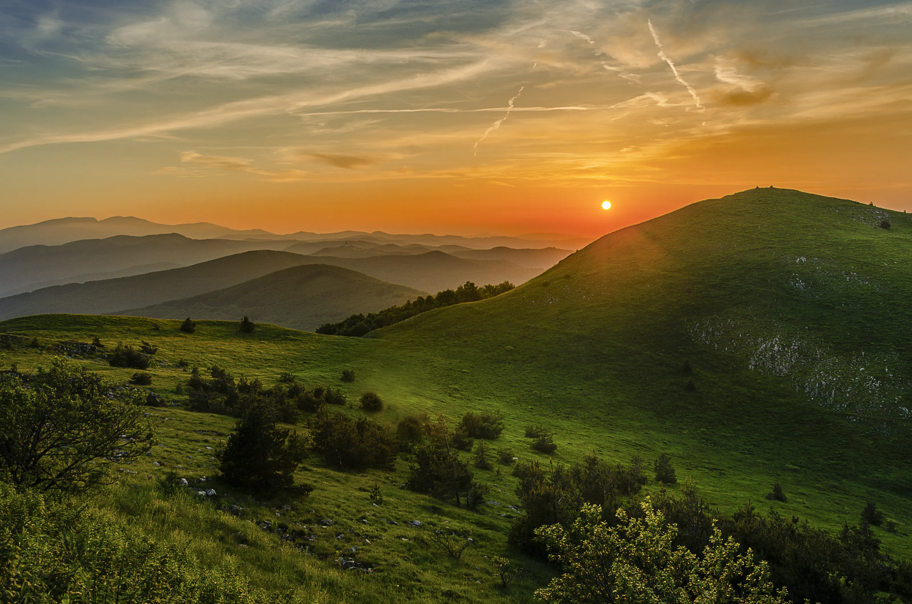 Orange sunset over green hills