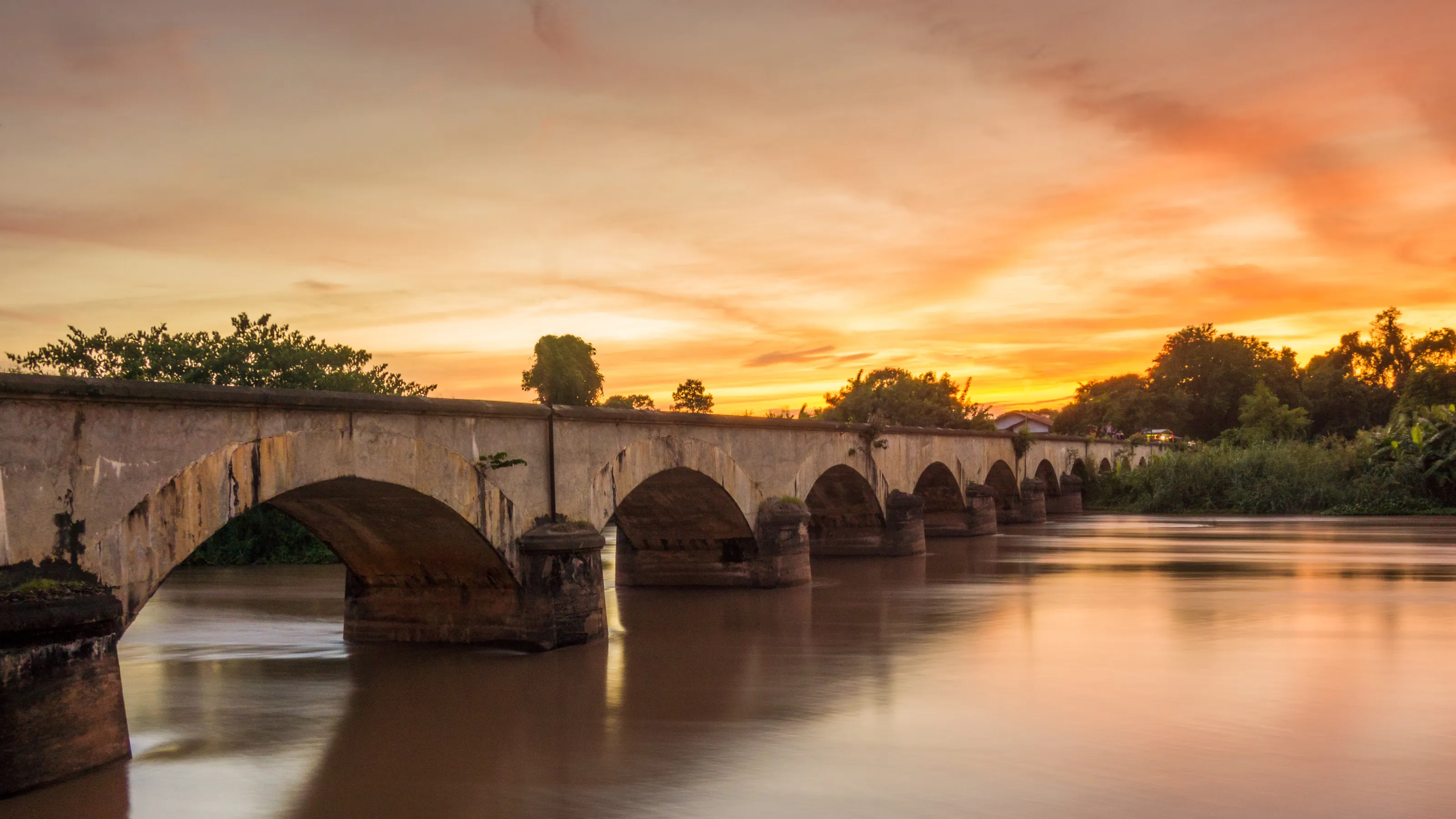 Sunset aver an old French bridge in South Laos