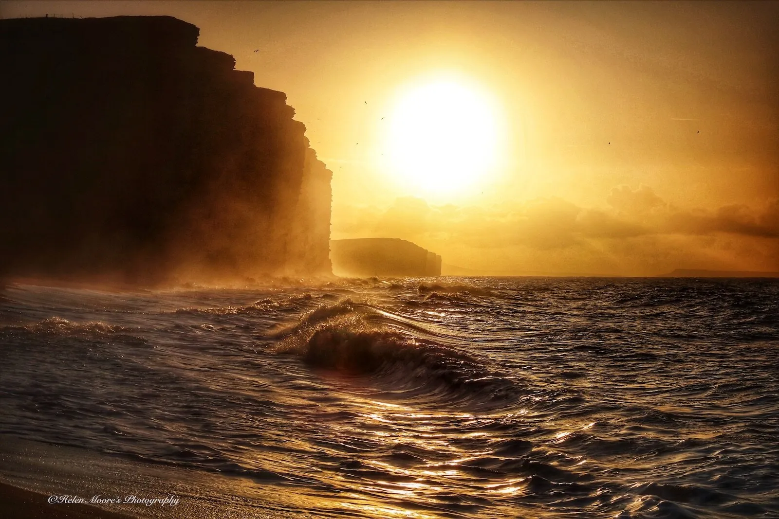 Sunrise over West Bay cliff & beach