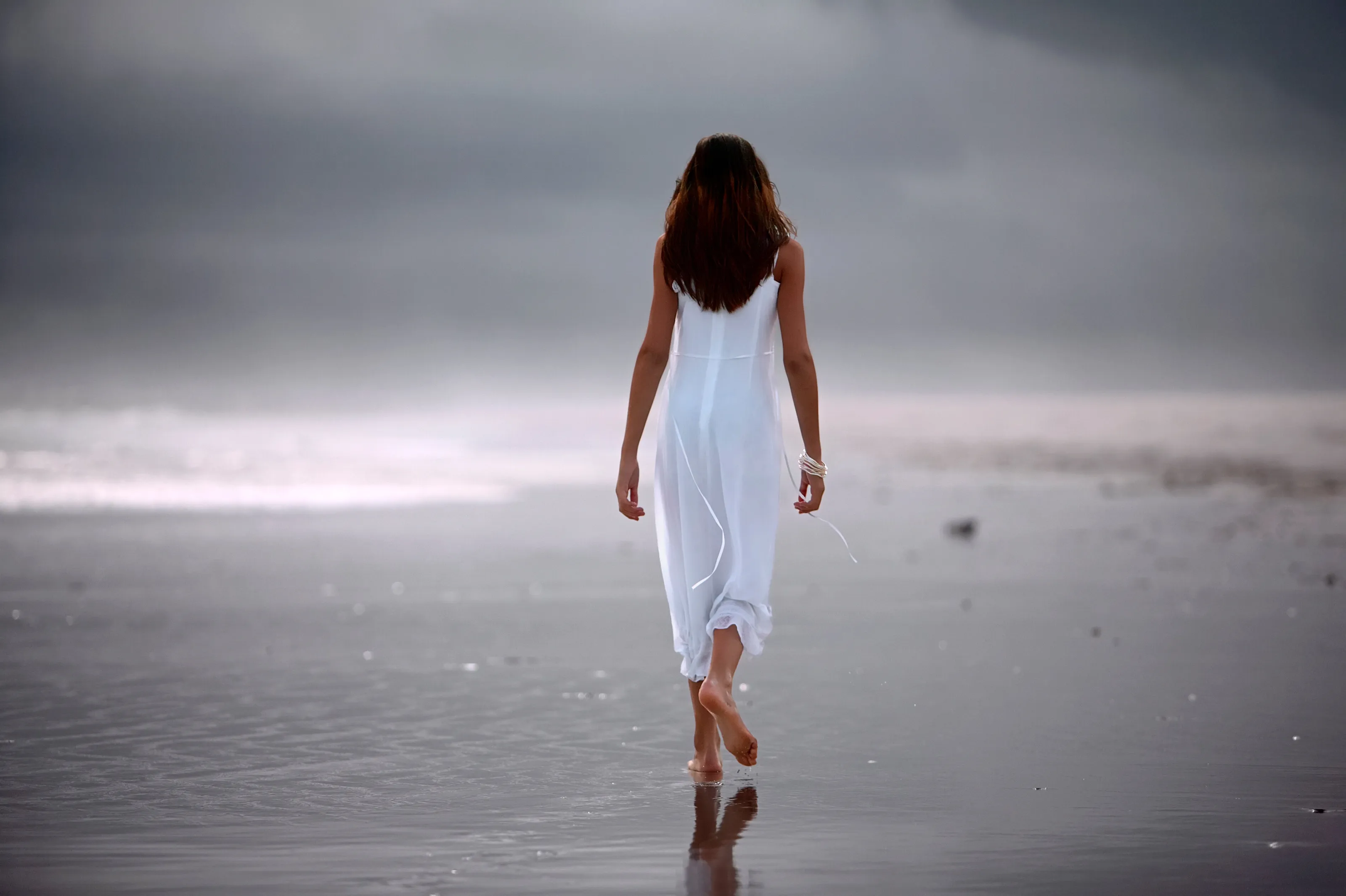 Young woman walking alone on the beach.
