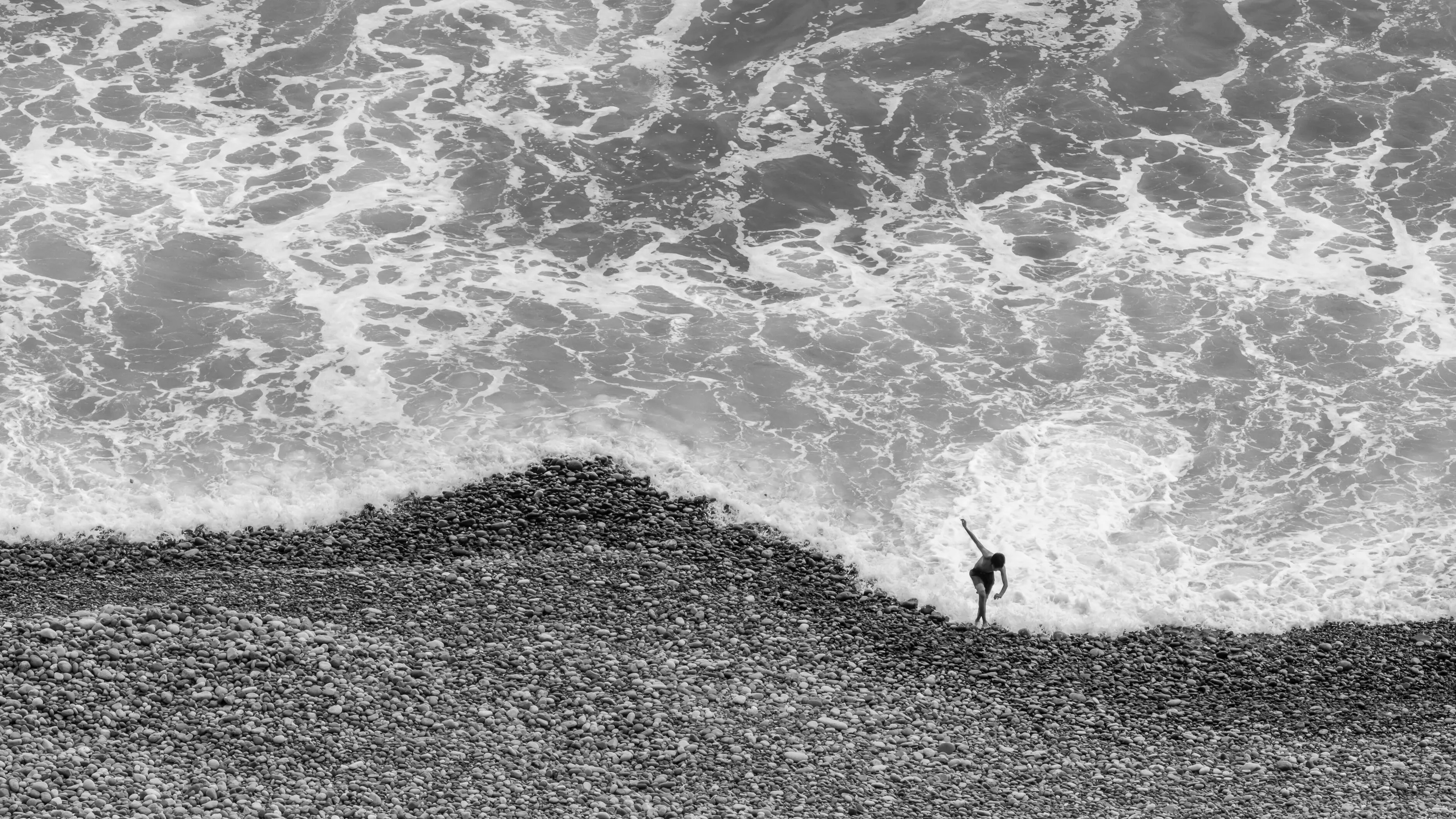 Young man walking on a stone beach in Costa Verde bay