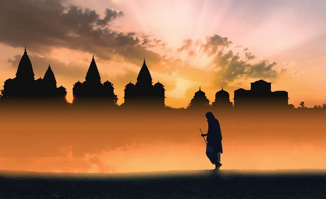 An old man walking on the bank of river with a landscape in background.