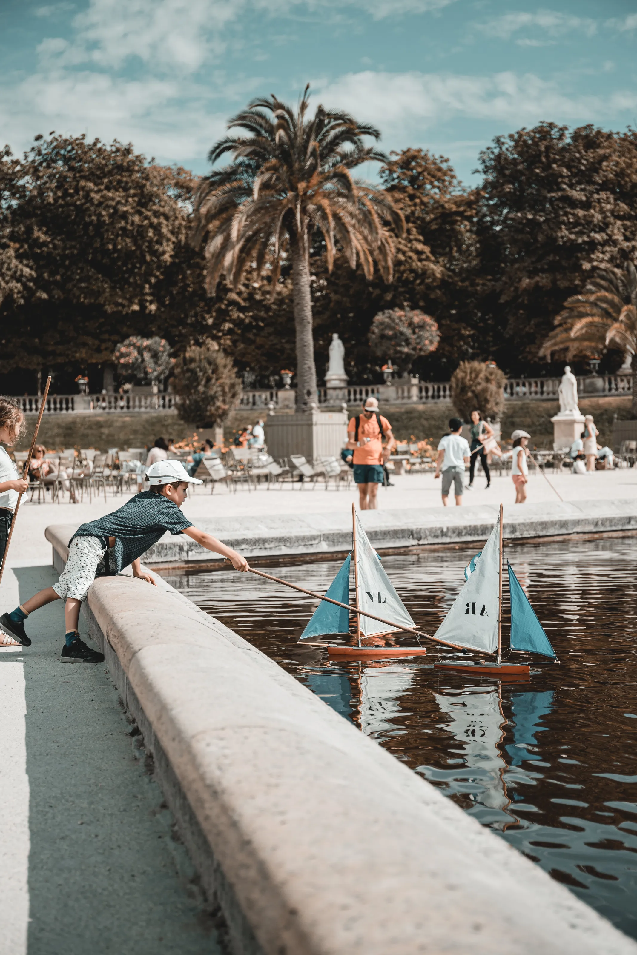 Boy Pushing Boats In A Paris Park