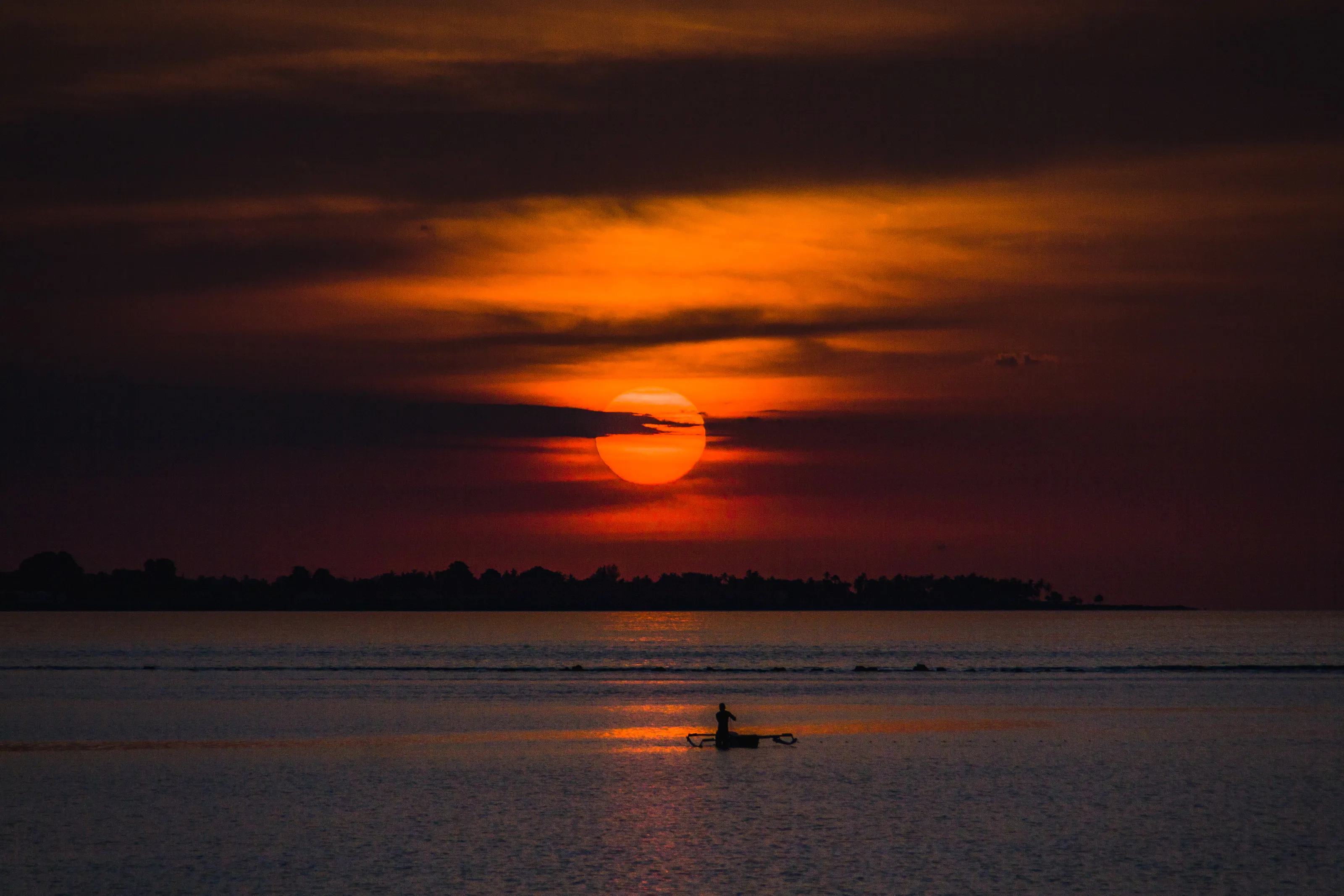 Fishermen at dusk welcome the sunset behind the city