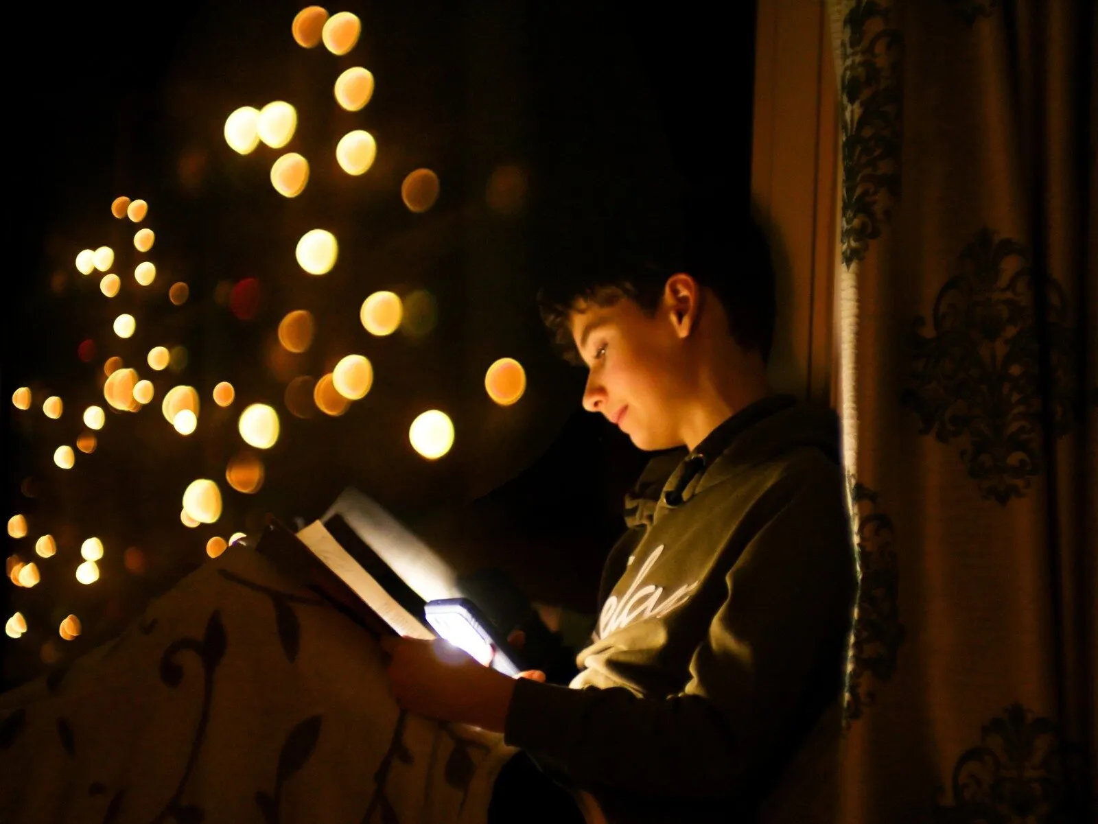 Dreamy portrait of a boy on magical Christmas lights