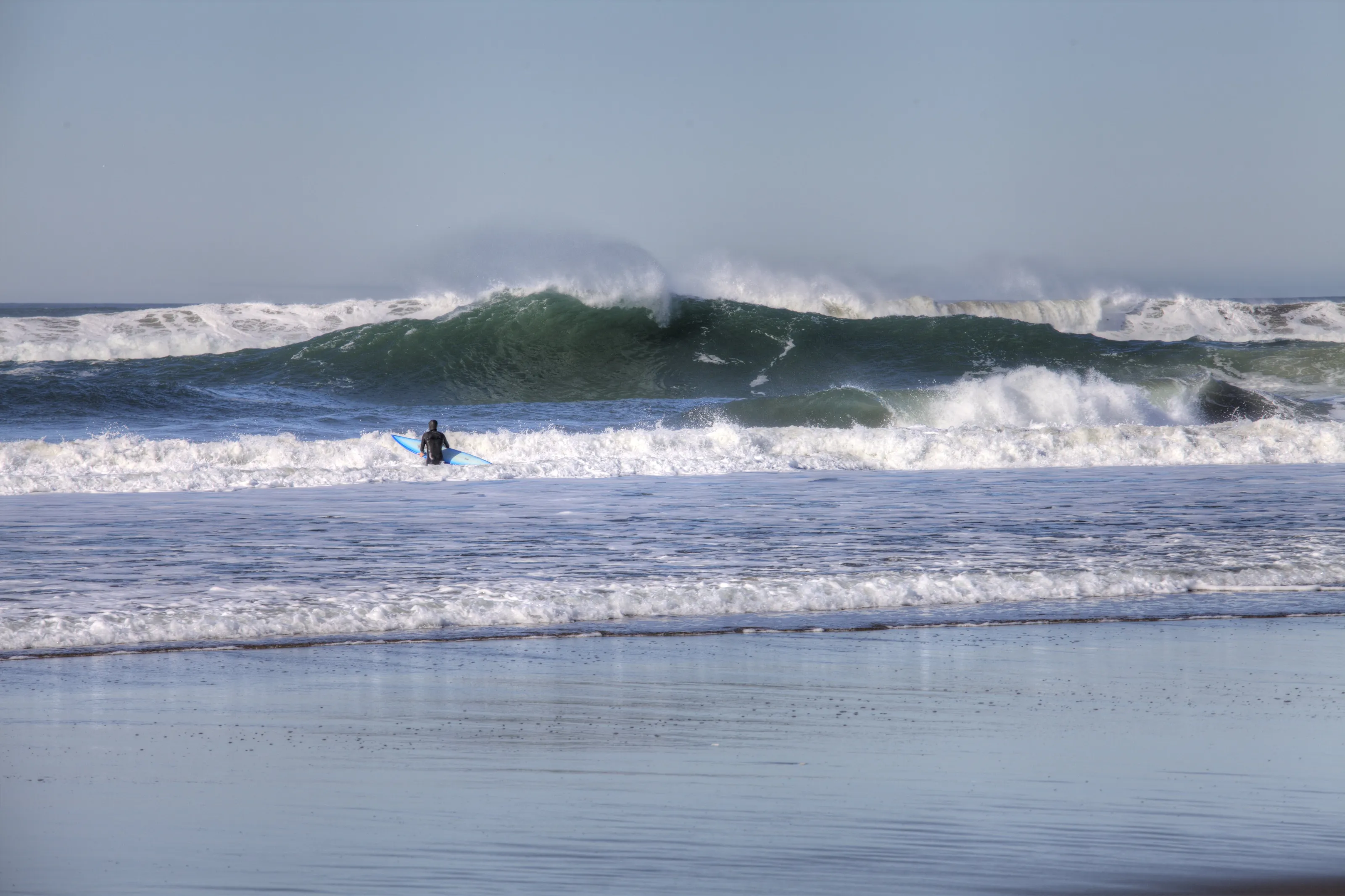 Surfer Watches A Large Wave Breaking At Ocean Beach.