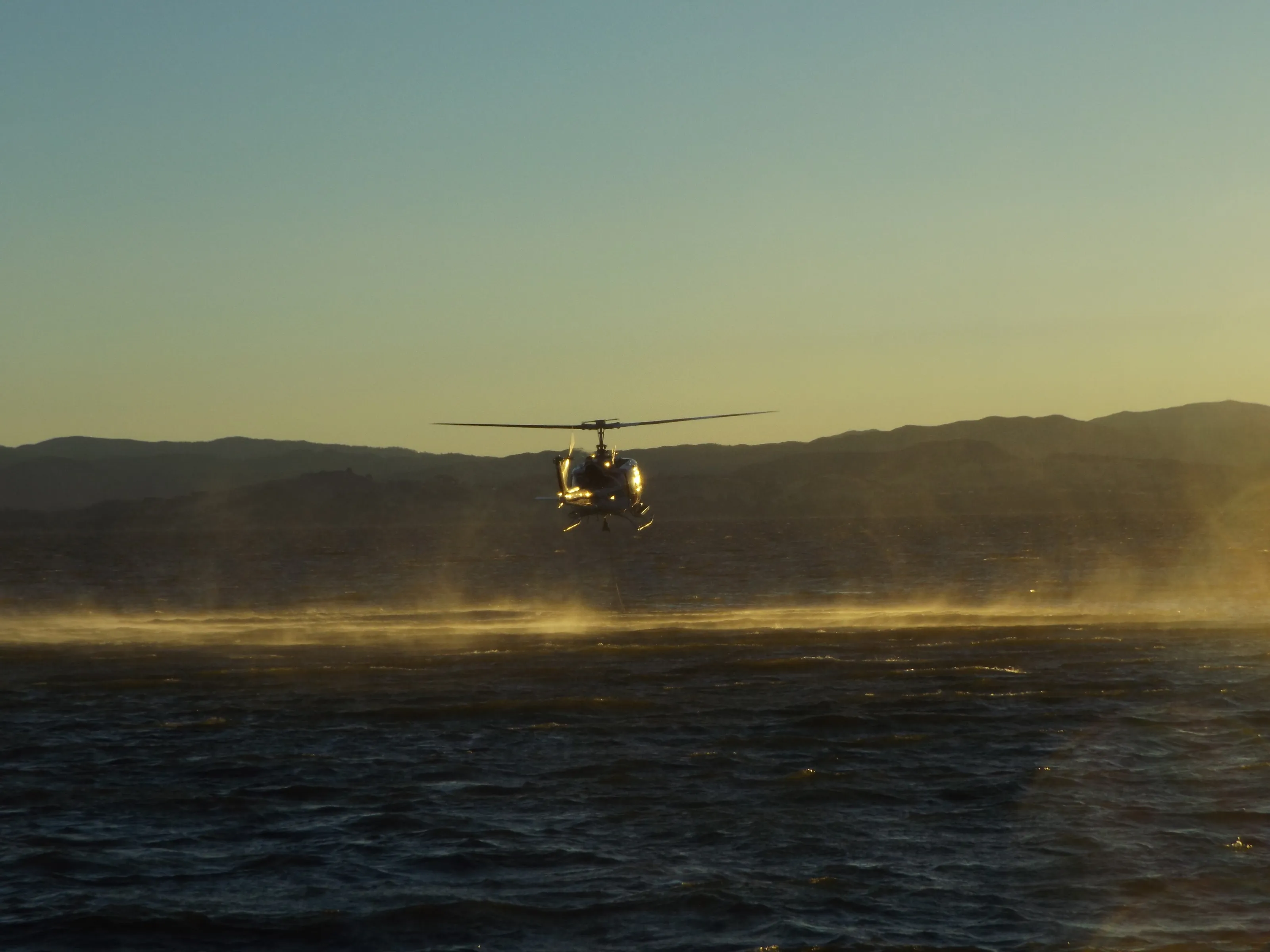 Firefighting Helicopter At Sunset Over The Lake