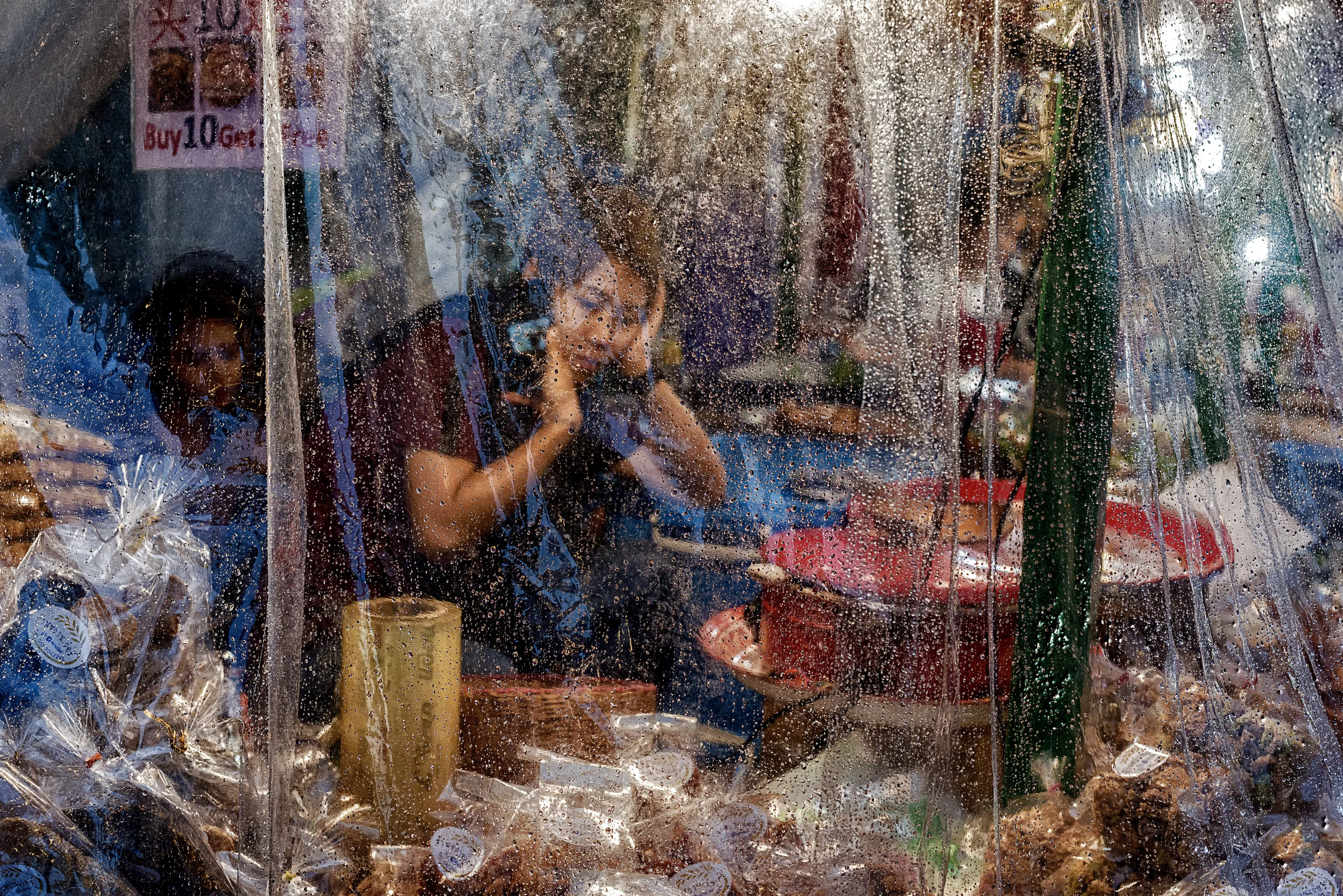 A Thai lady selling Traditional Delights at local market in Bangkok during rainfall