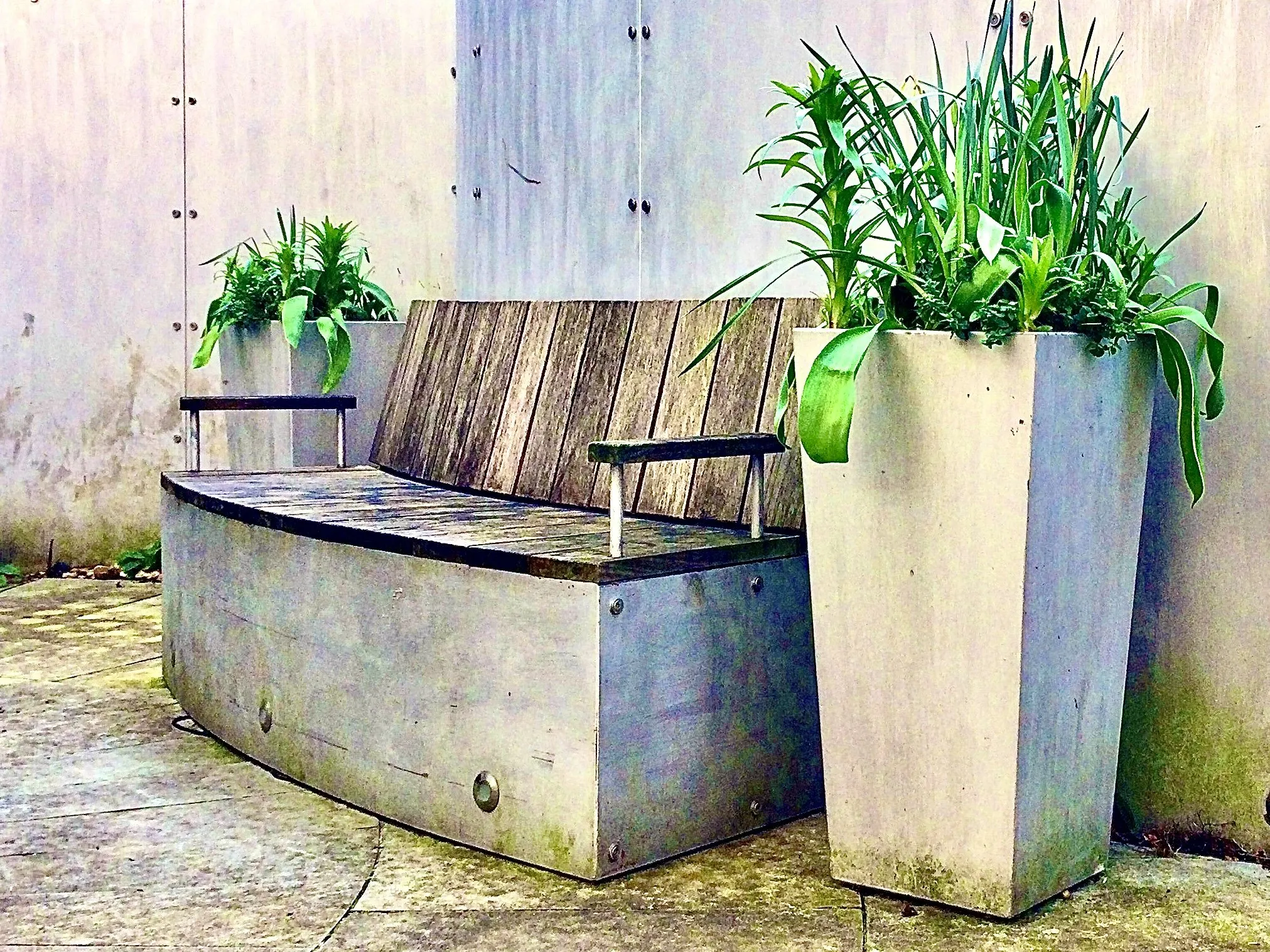 Concrete:   garden pots for plants and a bench.