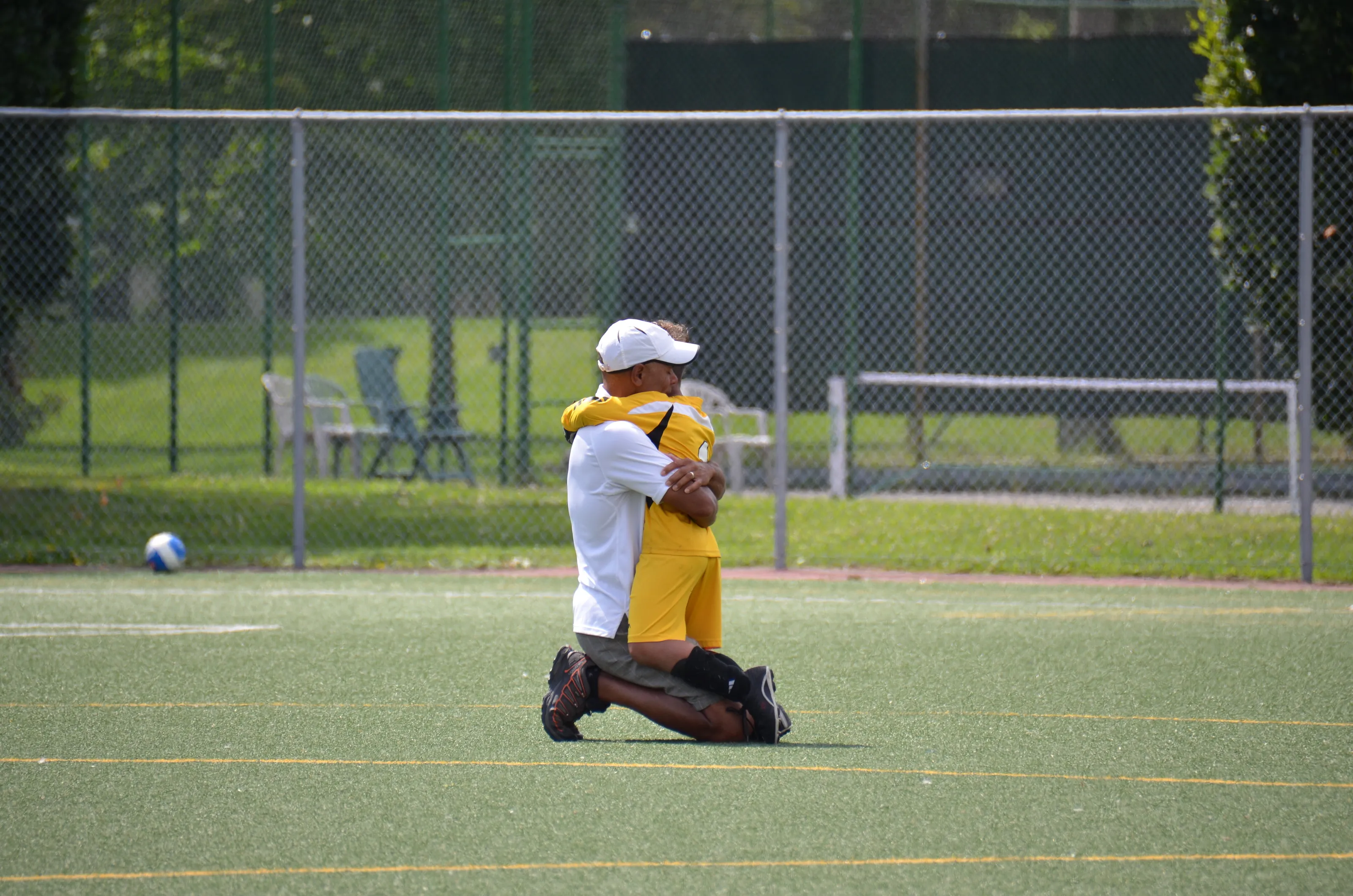 A father comforts his goal tender son after a soccer loss.